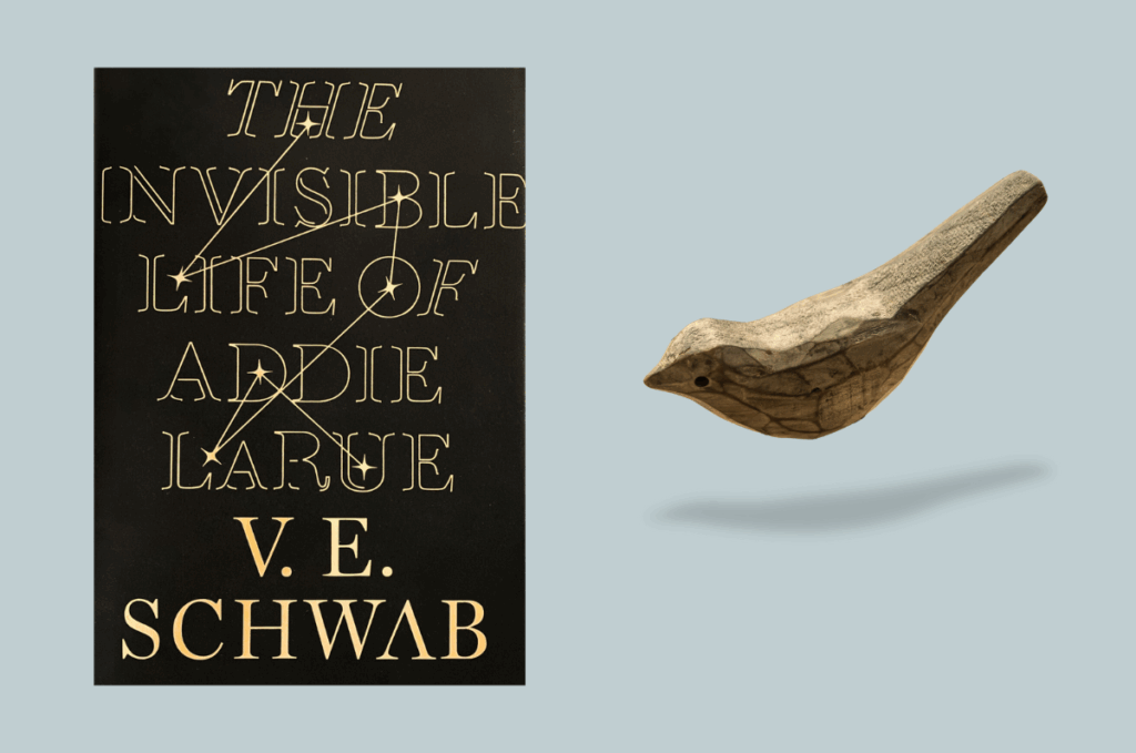 Image of cover of The Invisible Life of Addie Larue with a wooden bird to the right